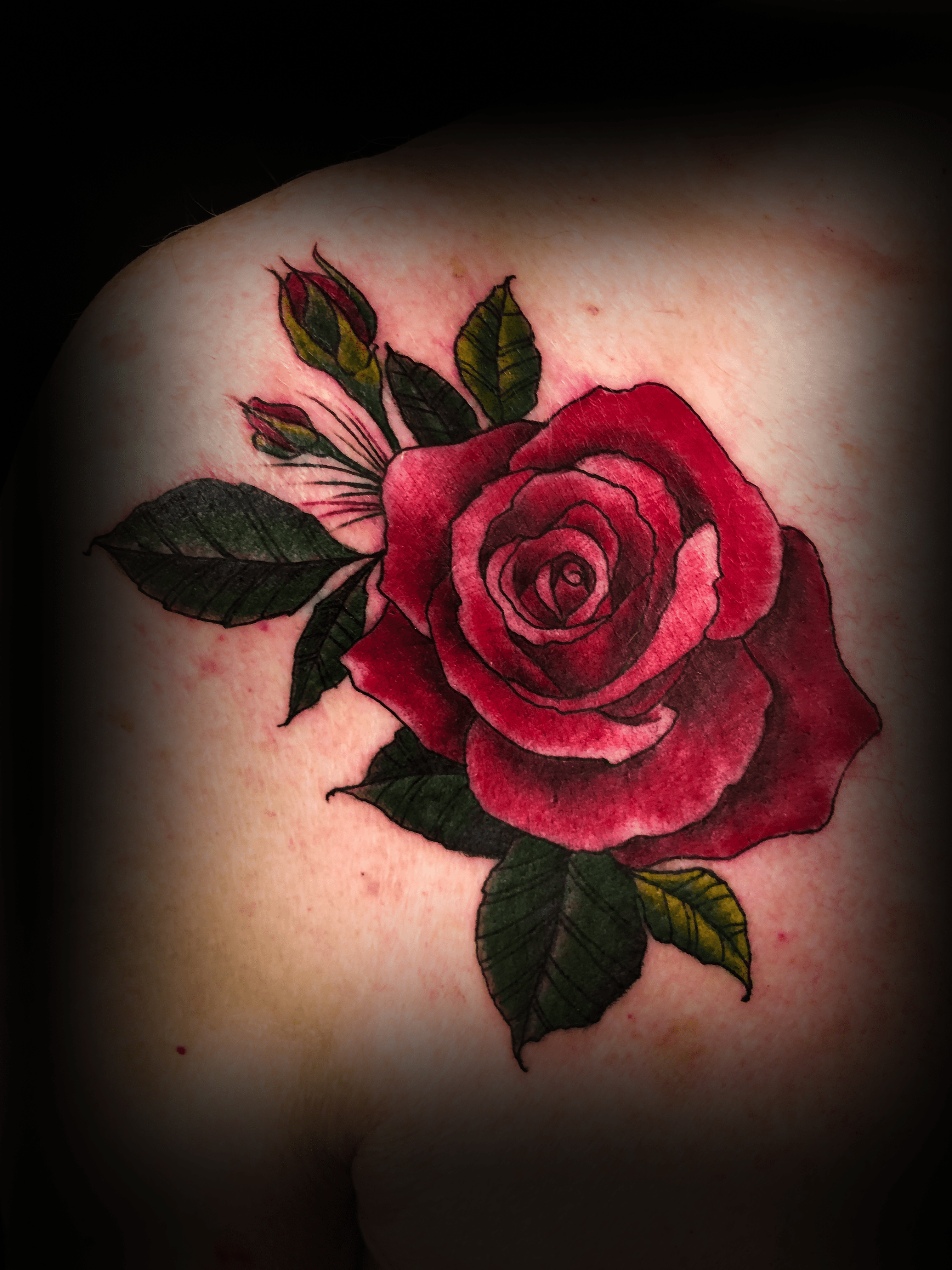 An image of a custom tattoo from Kevin Younger's Lucky Cat Tattoo Parlour: a design featuring a bright red rose with green leaves