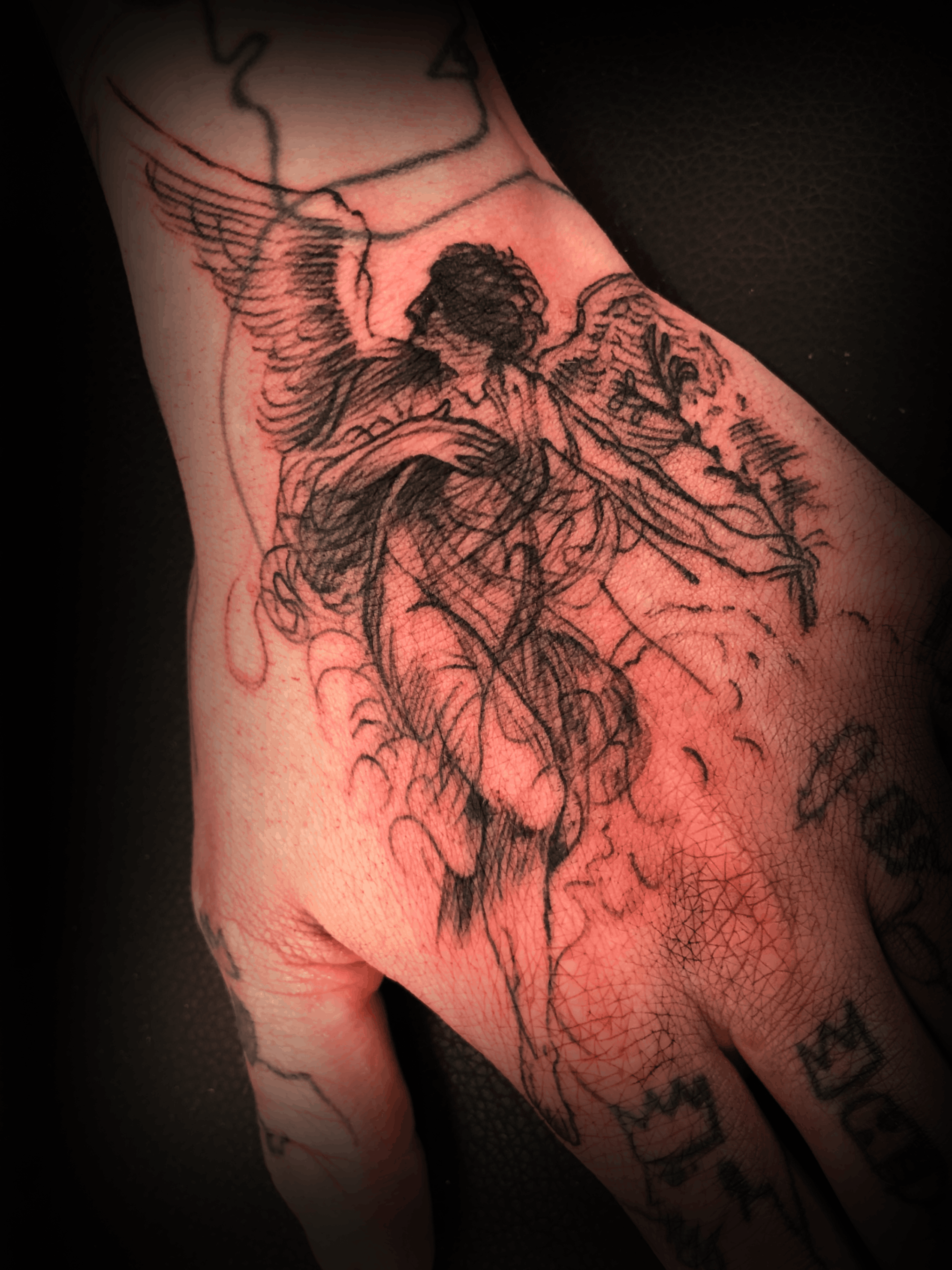 An image of a custom tattoo from Kevin Younger's Lucky Cat Tattoo Parlour: a design featuring a sketched flying angel on a hand