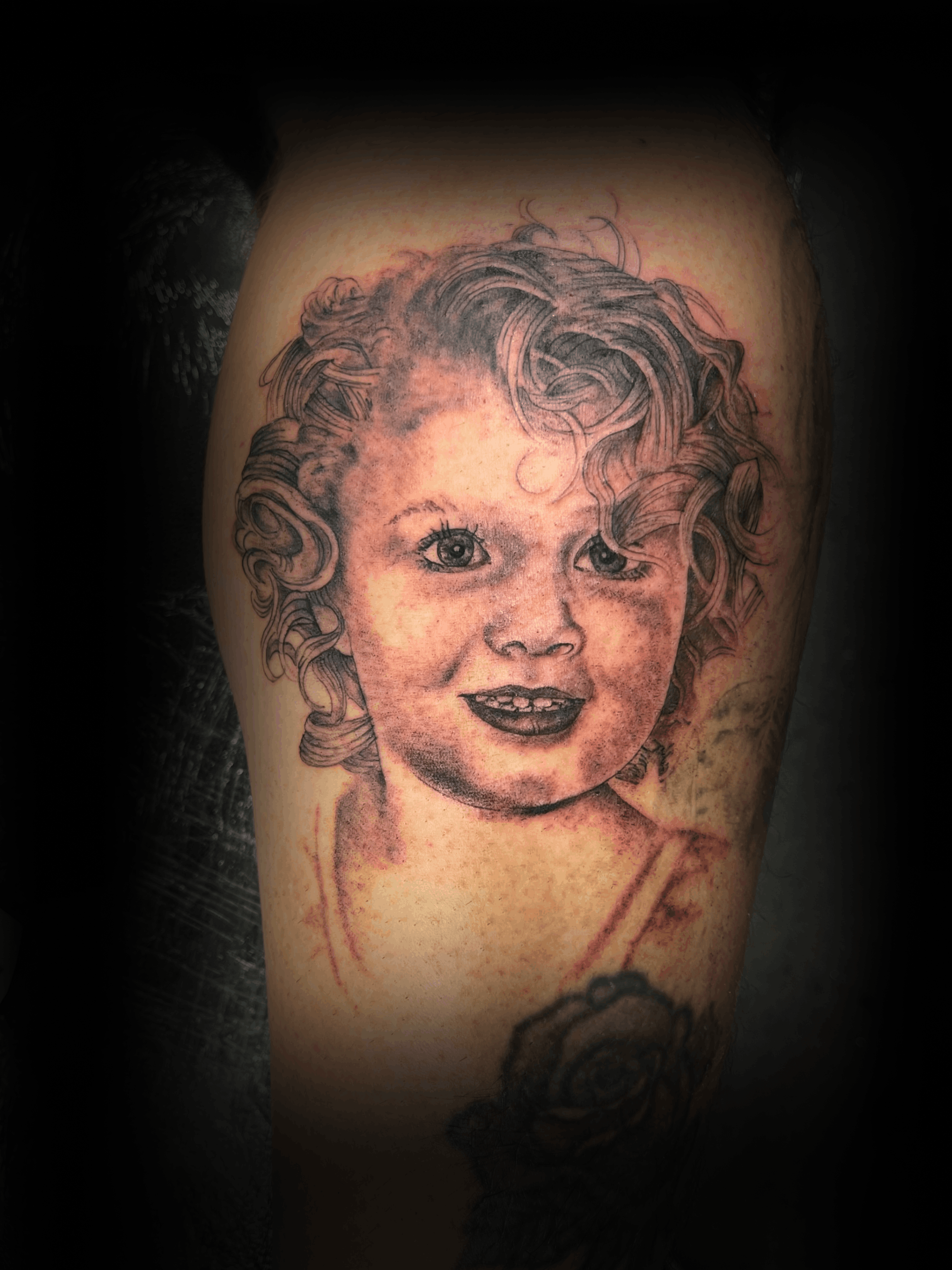 An image of a custom tattoo from Kevin Younger's Lucky Cat Tattoo Parlour: a design featuring a black and grey realistic portrait of a female