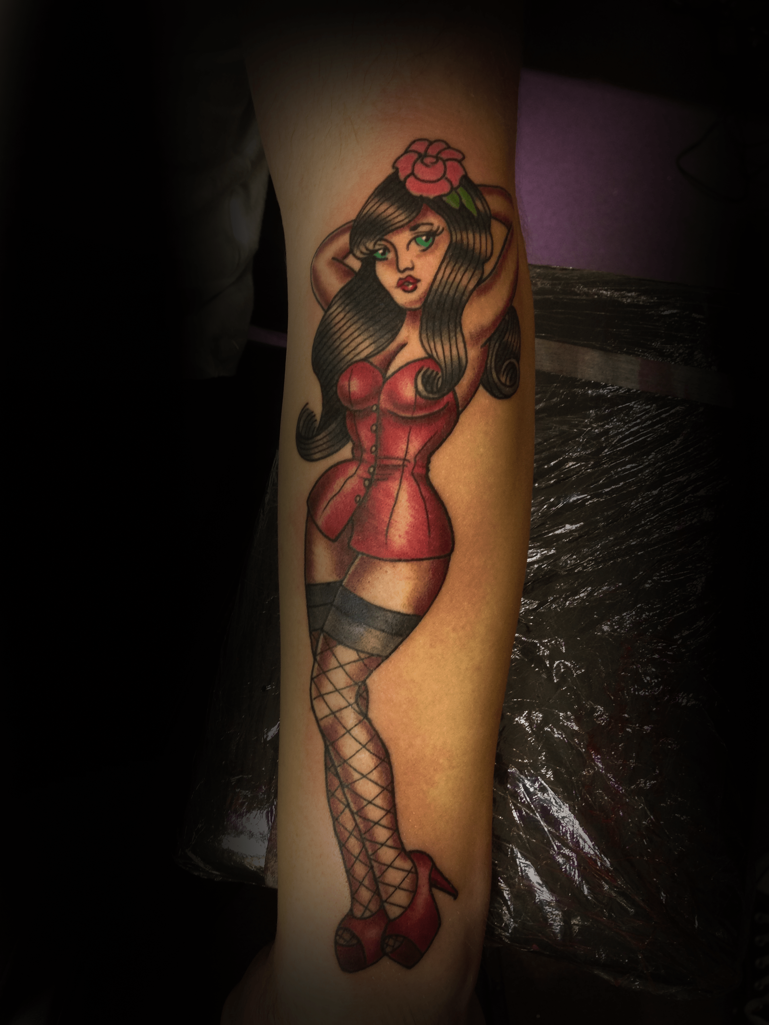 An image of a custom tattoo from Kevin Younger's Lucky Cat Tattoo Parlour: a design featuring a pin up girl in a red dress and hat