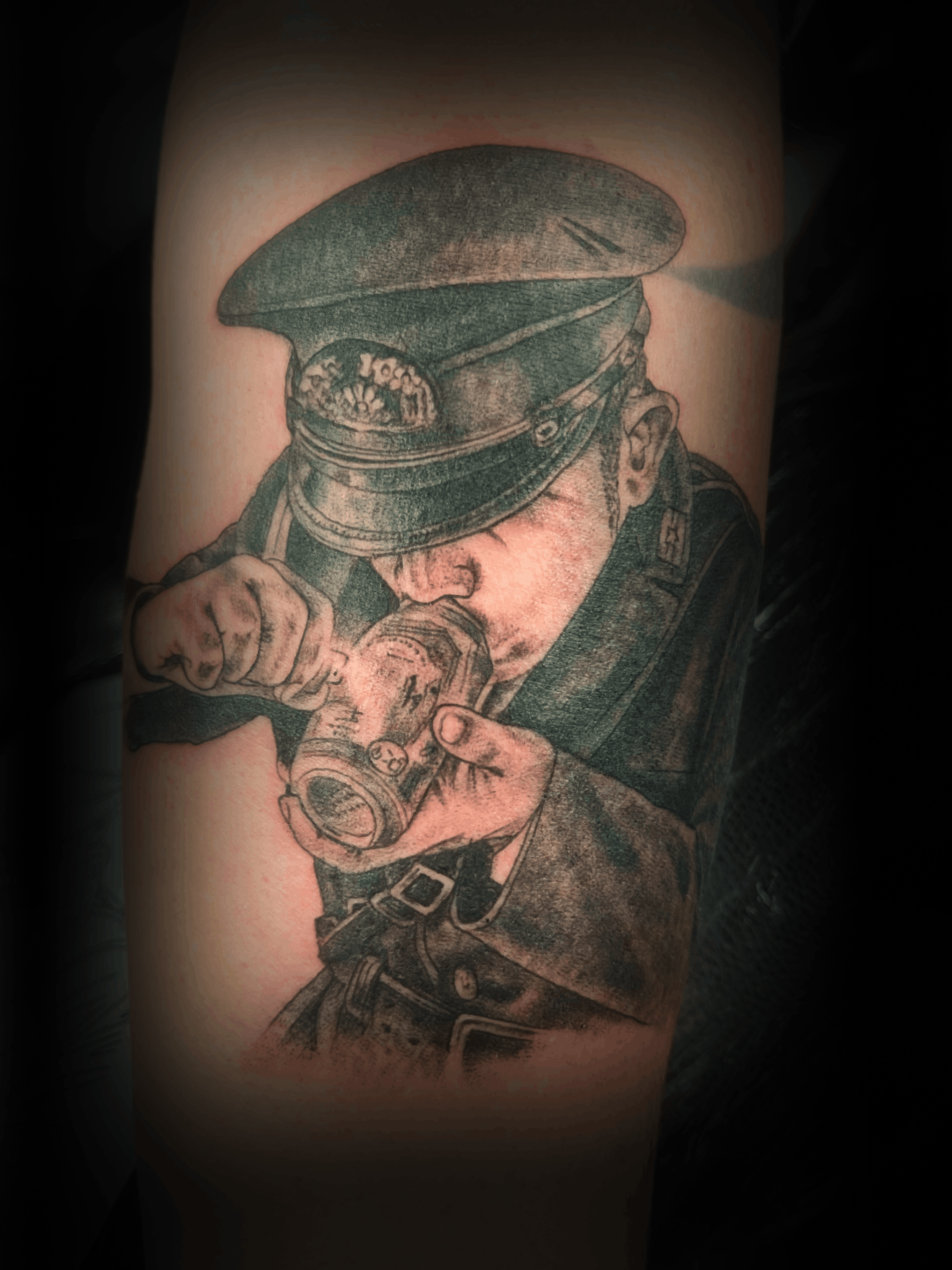 An image of a custom tattoo from Kevin Younger's Lucky Cat Tattoo Parlour: a design featuring a black and grey man in uniform smoking a pipe
