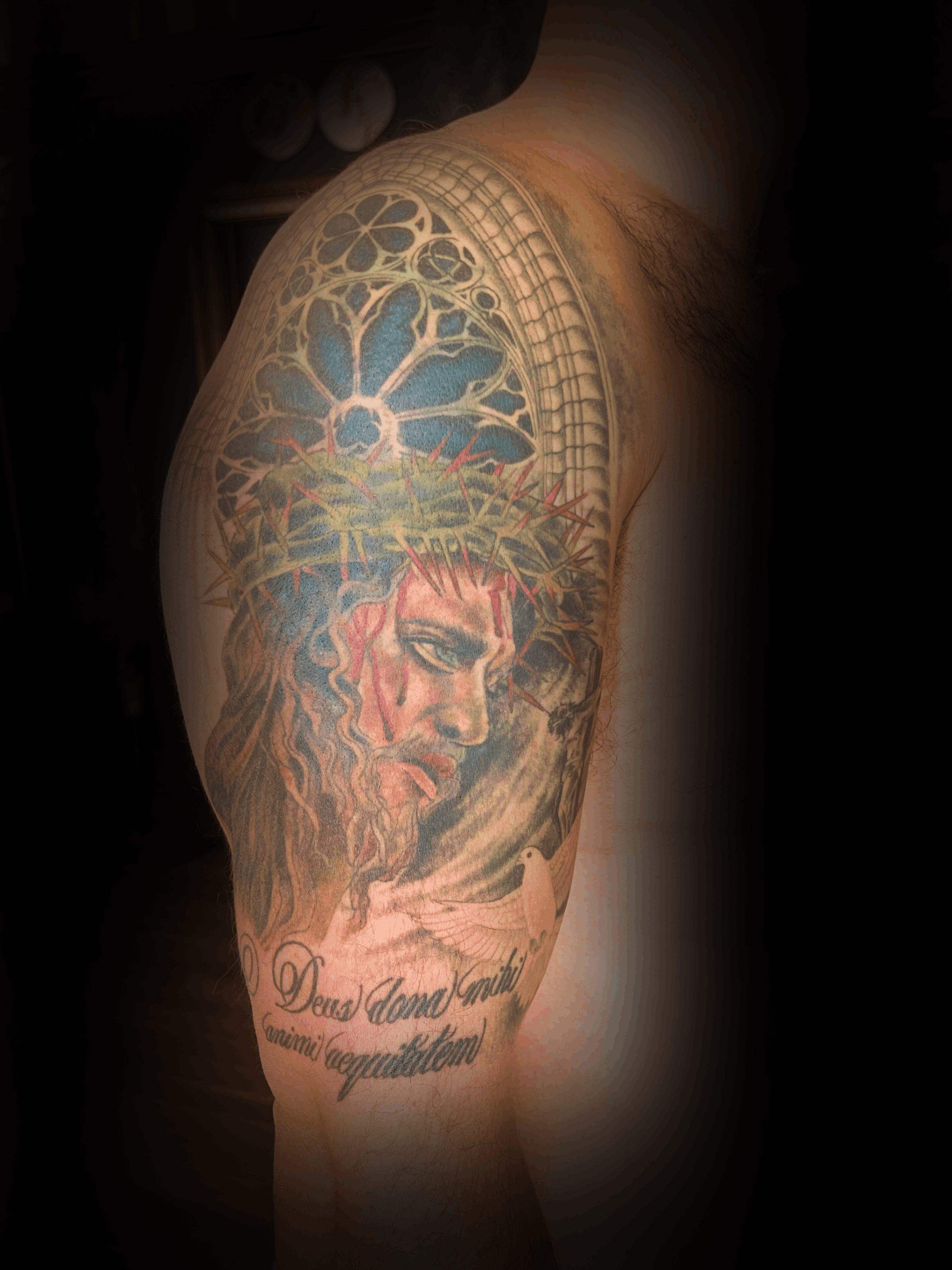 An image of a custom tattoo from Kevin Younger's Lucky Cat Tattoo Parlour: a design featuring Jesus Christ with church windows behind