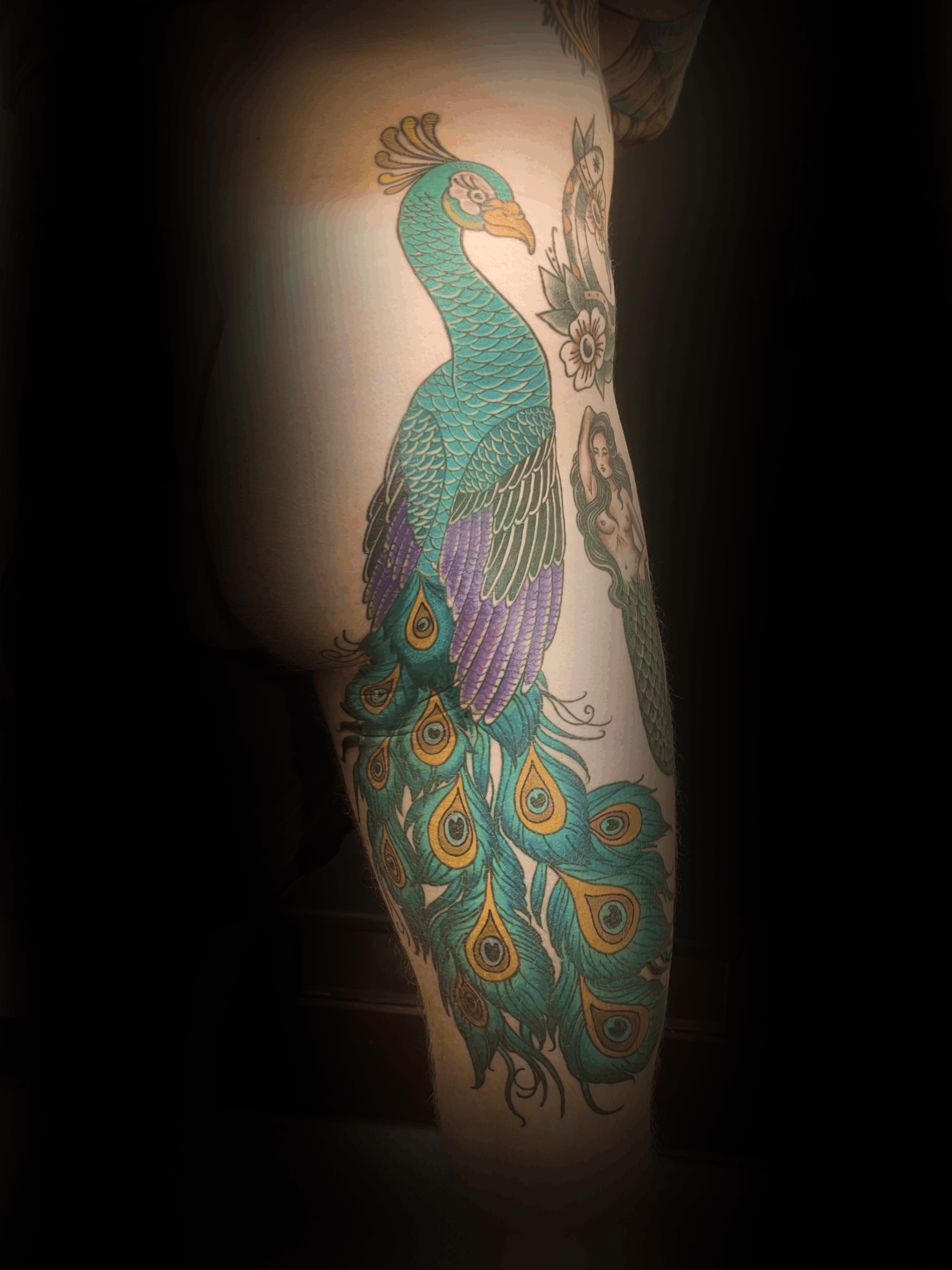 An image of a custom tattoo from Kevin Younger's Lucky Cat Tattoo Parlour: a design featuring a colourful Peacock