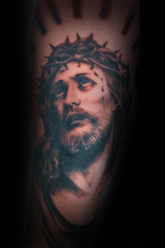 An image of a custom tattoo from Kevin Younger's Lucky Cat Tattoo Parlour: a design featuring a black and grey portrait of Jesus Christ with thorns
