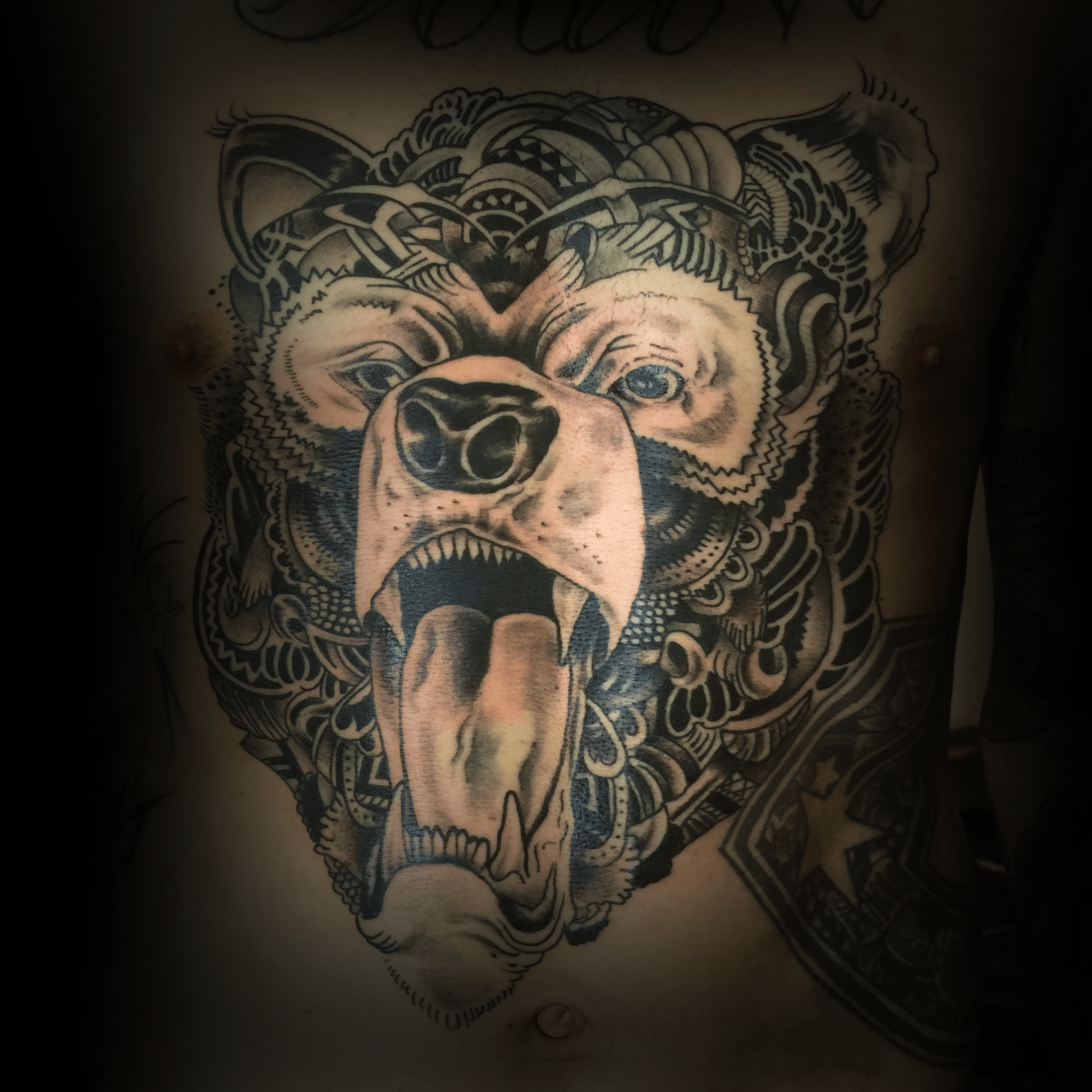 An image of a custom tattoo from Kevin Younger's Lucky Cat Tattoo Parlour: a design featuring a black and grey bear with patterns throughout