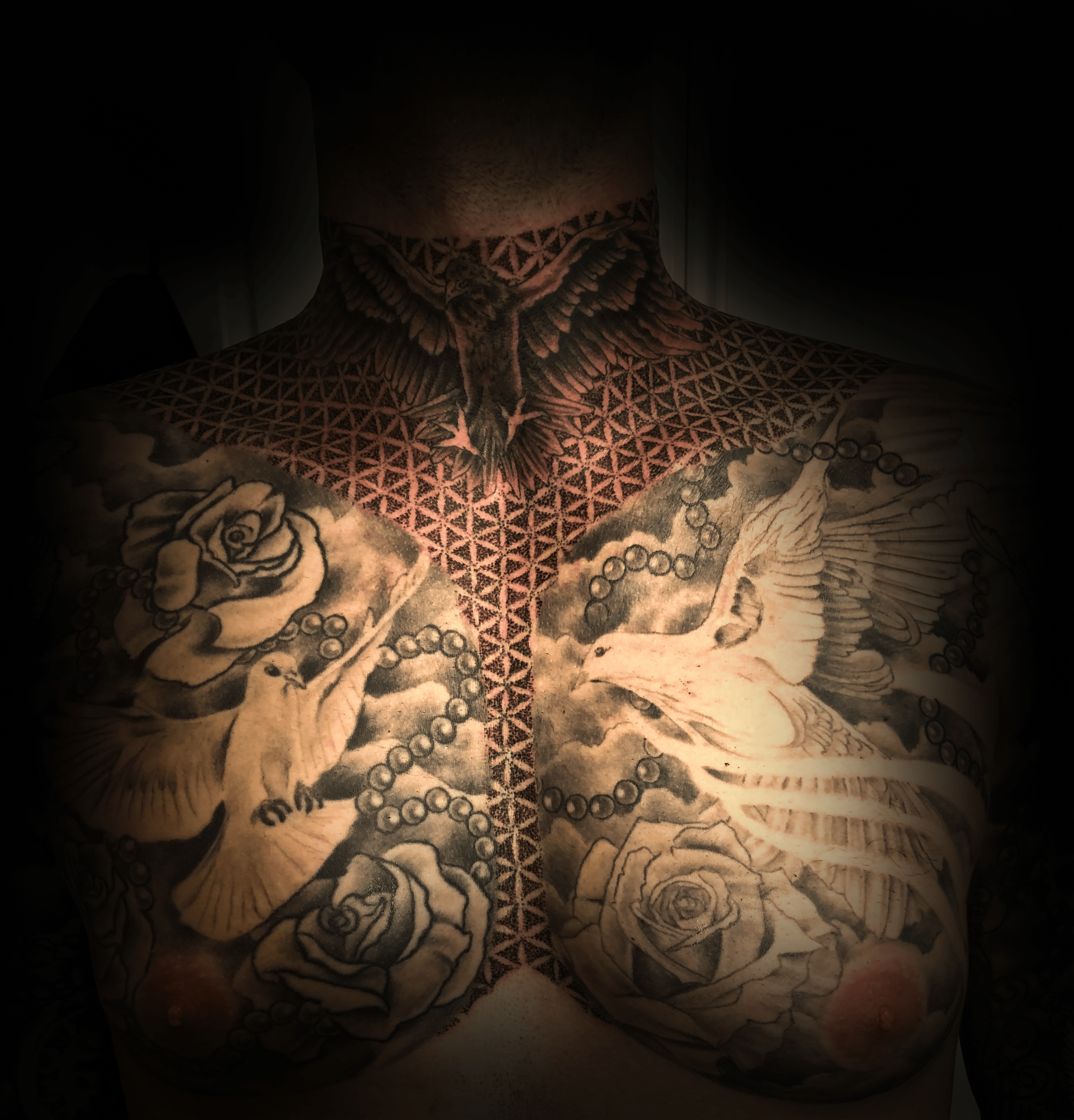 An image of a custom tattoo from Kevin Younger's Lucky Cat Tattoo Parlour: a chest and neck design featuring doves, roses, and clouds with mandala type patterns
