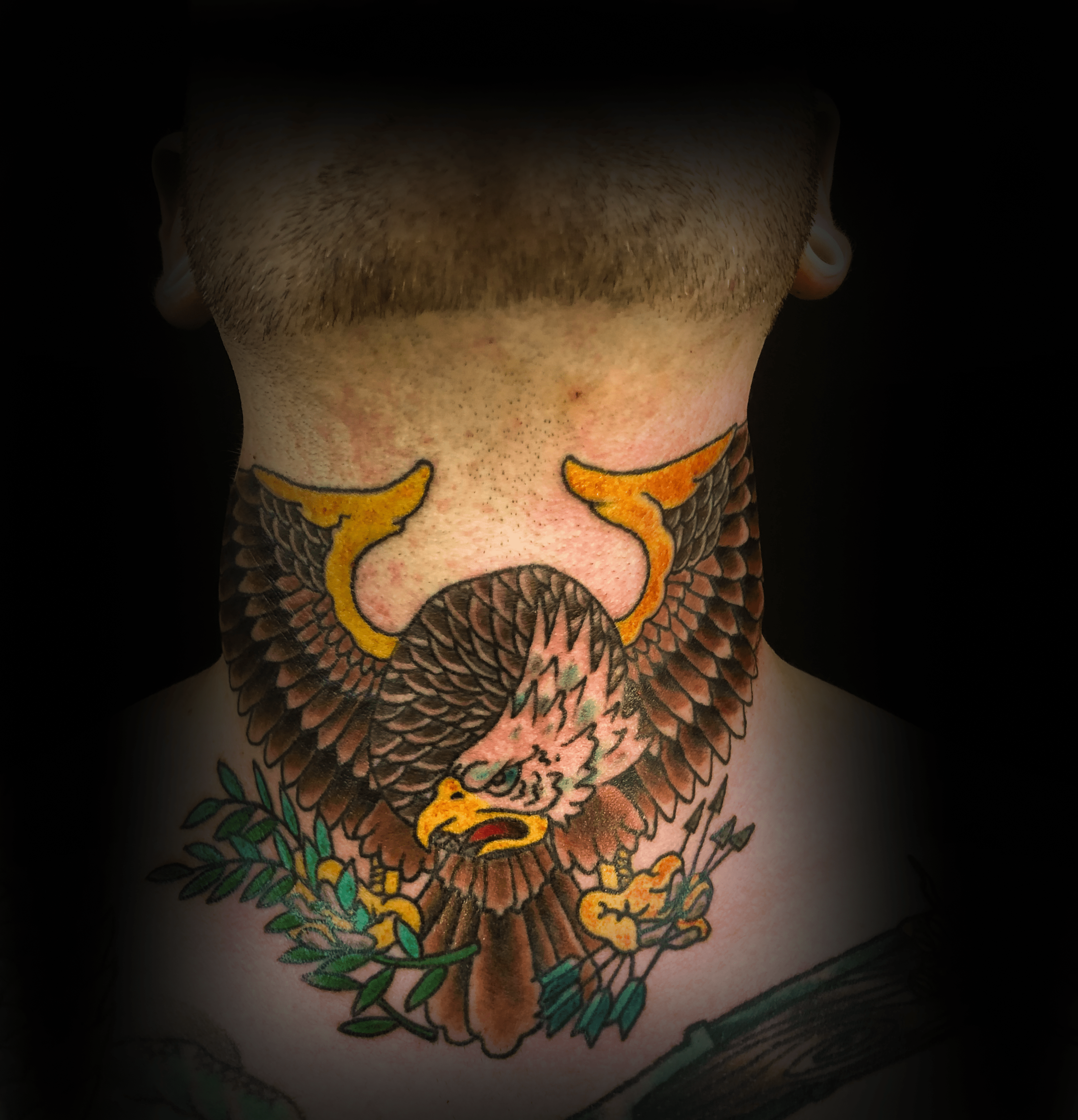 An image of a custom tattoo from Kevin Younger's Lucky Cat Tattoo Parlour: a neck design featuring a colourful eagle holding arrows